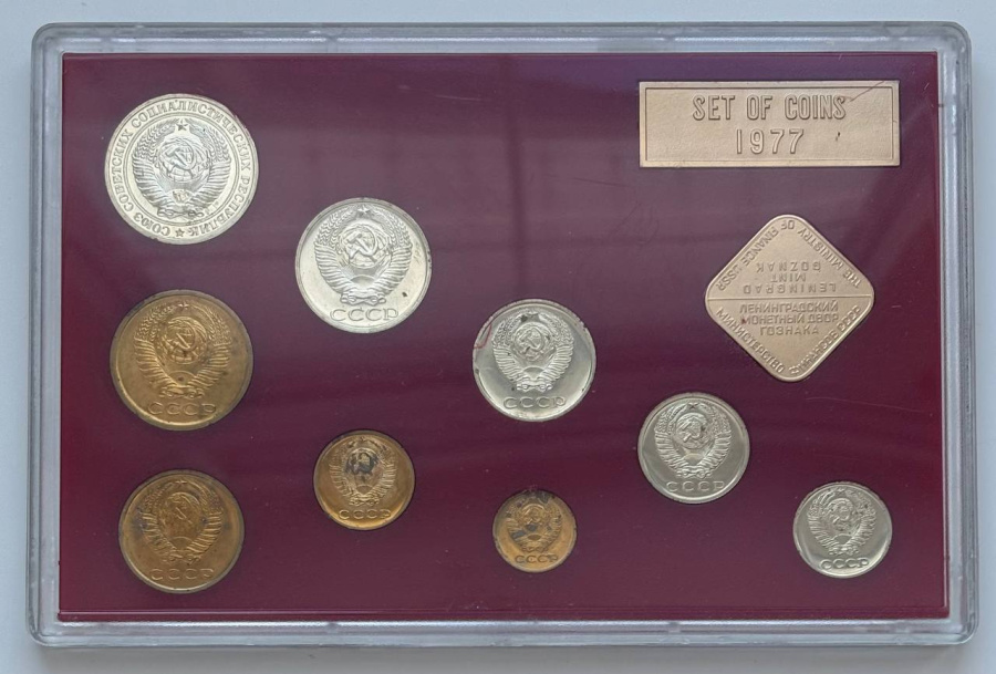 Годовой набор монет улучшенного качества Госбанка СССР 1977 г. ЛМД: 1 рубль, 50 копеек, 20 копеек, 15 копеек, 10 копеек. Медно-никелевый сплав. 5 копеек, 3 копейки, 2 копейки, 1 копейка. Медно-цинковый сплав. Жесткий пластик, пластмассовый трафарет красного цвета, с ромбовидным жетоном ЛМД и годовой плашкой из алюминия. Сохранность почти отличная, патина, пятна. Петров, Федорин №№ 345, 346, 348, 350, 351, 354, 356, 361, 364. Набор вложен в оригинальную картонную коробку оливкового цвета.