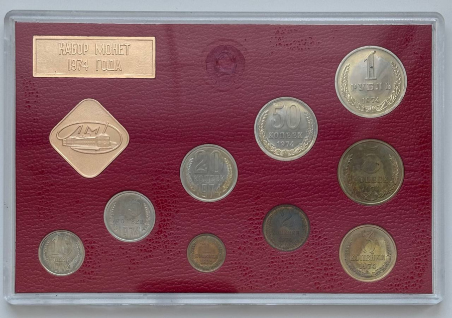 Годовой набор монет улучшенного качества Госбанка СССР 1974 г. ЛМД: 1 рубль, 50 копеек, 20 копеек, 15 копеек, 10 копеек. Медно-никелевый сплав. 5 копеек, 3 копейки, 2 копейки, 1 копейка. Медно-цинковый сплав. Жесткий пластик, ледериновый трафарет красного цвета, с ромбовидным жетоном ЛМД и годовой плашкой из алюминия. В состав набора входит редкая «перепутка» 20 копеек с аверсом 3 копеек-ленты герба сильно вогнутые. Сохранность отличная. Петров, Федорин №№ 306, 307, 309 (Р04), 310, 311, 312, 313, 317, 319. Набор вложен в оригинальную картонную коробку оливкового цвета. 